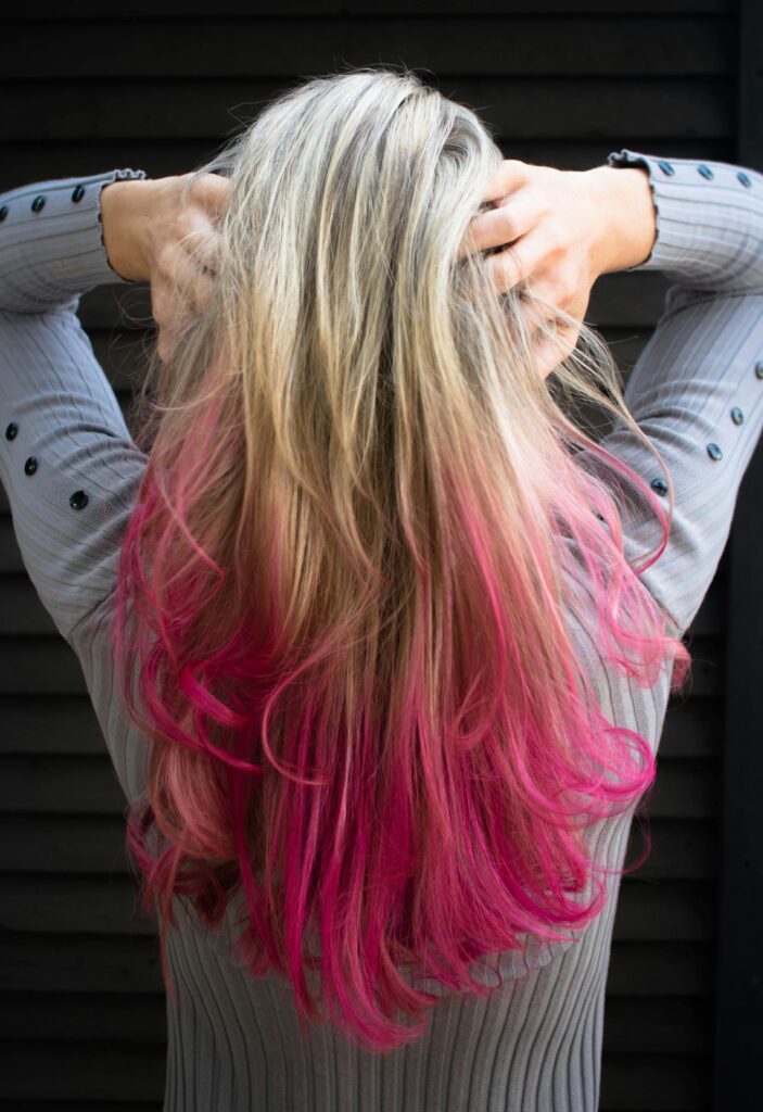 Close-up of a woman with blonde and pink ombre hair in a stylish pose.